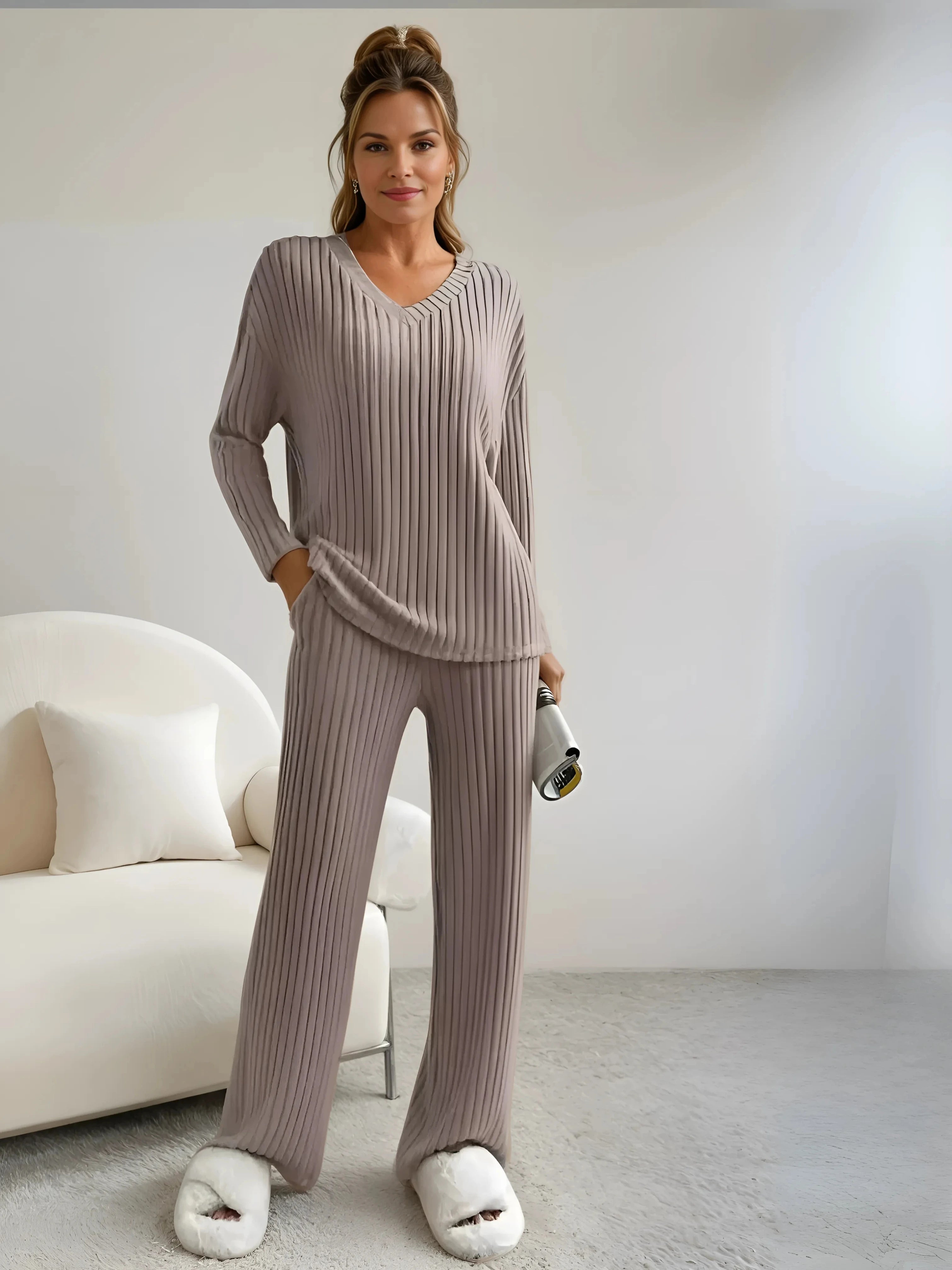 Femme élégante portant un ensemble homewear beige en tissu plissé fluide, idéal pour une tenue d'intérieur cosy et raffinée. Confort et style réunis pour des moments de détente à la maison.