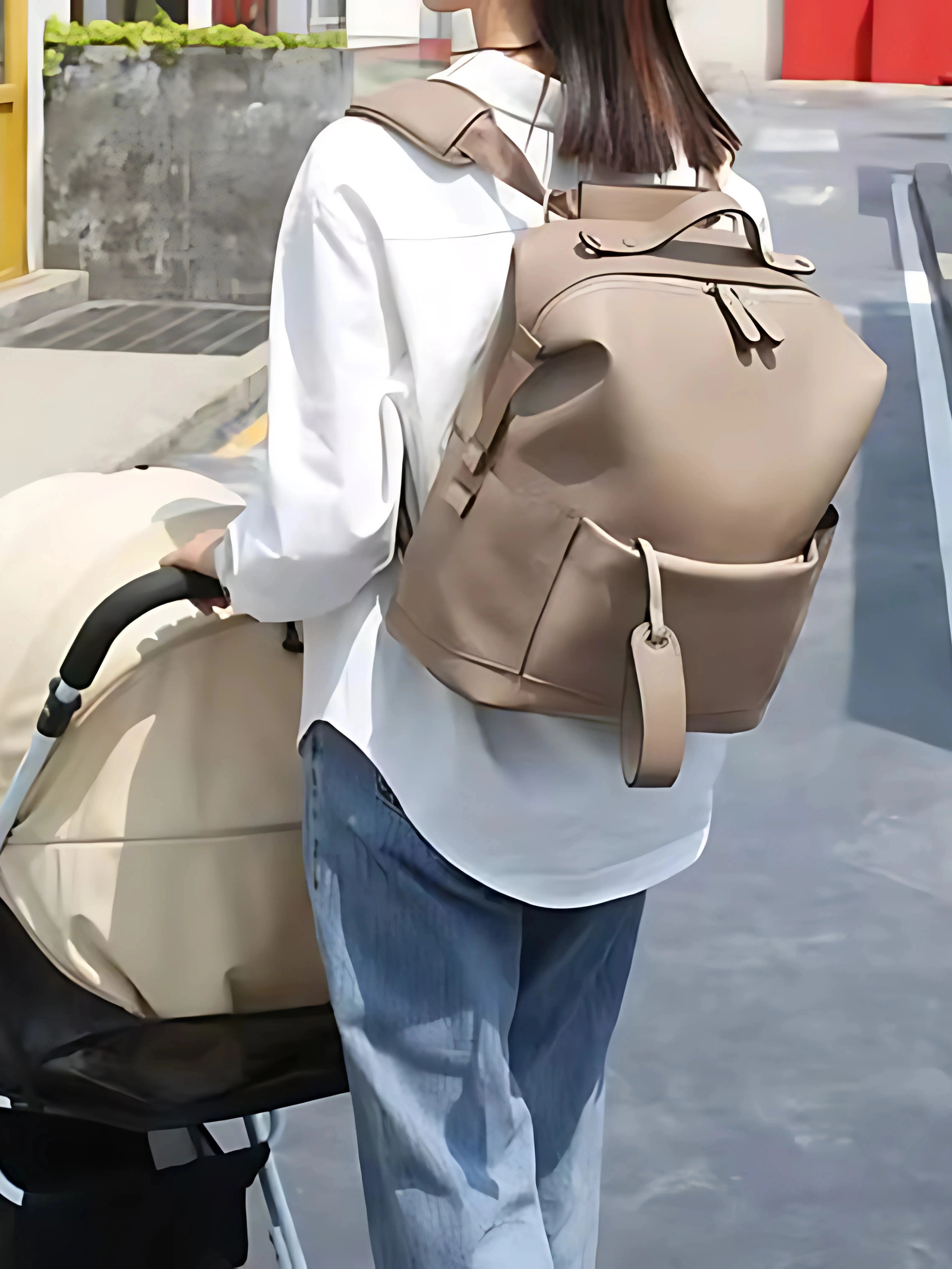 Sac à langer beige porté en sac à dos par un parent, design élégant et pratique, idéal pour les sorties avec une poussette.