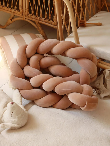 Tresse de lit bébé terracotta posée sur un tapis doux, pour une chambre sécurisée au style bohème et naturel.