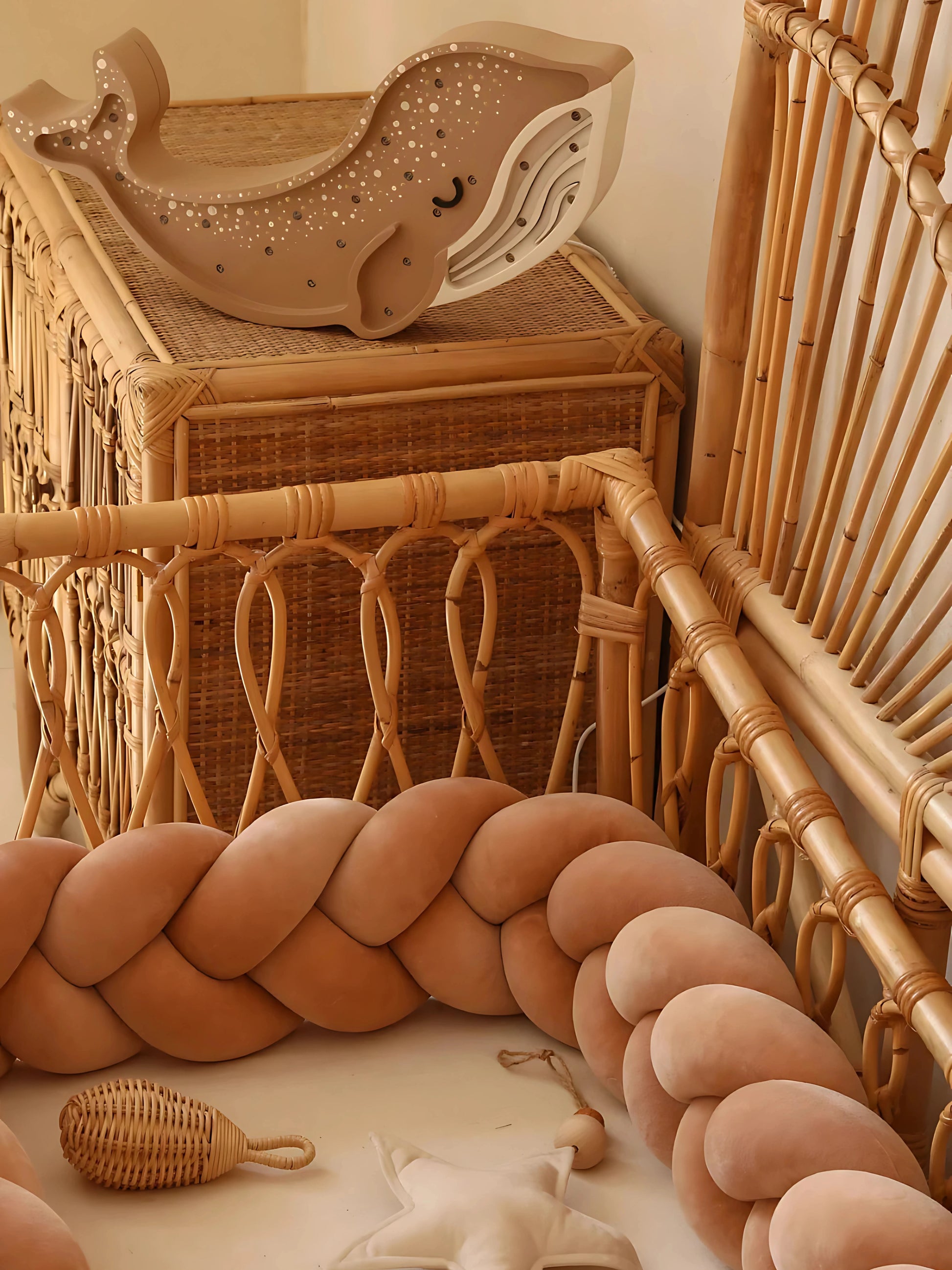 Tresse de lit bébé terracotta dans un berceau en rotin, avec décoration naturelle et jouets en bois.