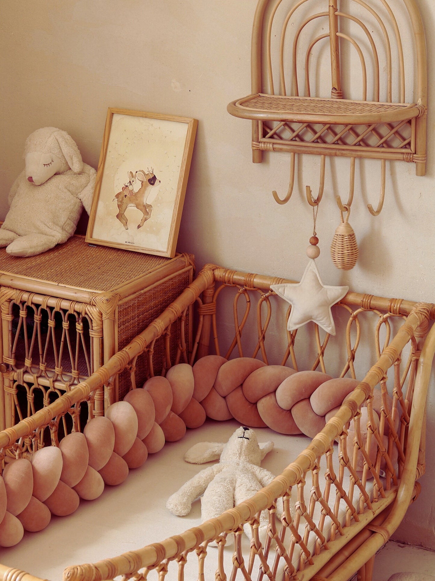 Tresse de lit terracotta dans un berceau en rotin avec déco animaux et peluche lapin pour une chambre apaisante.
